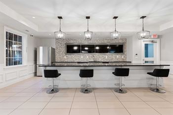 A modern kitchen with a bar area and black stools.